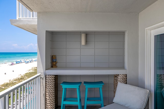 balcony featuring a view of the beach and a water view