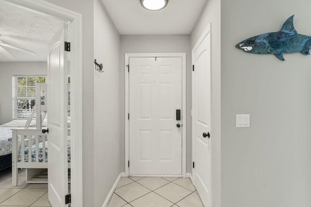 doorway to outside with ceiling fan, light tile patterned floors, and a textured ceiling