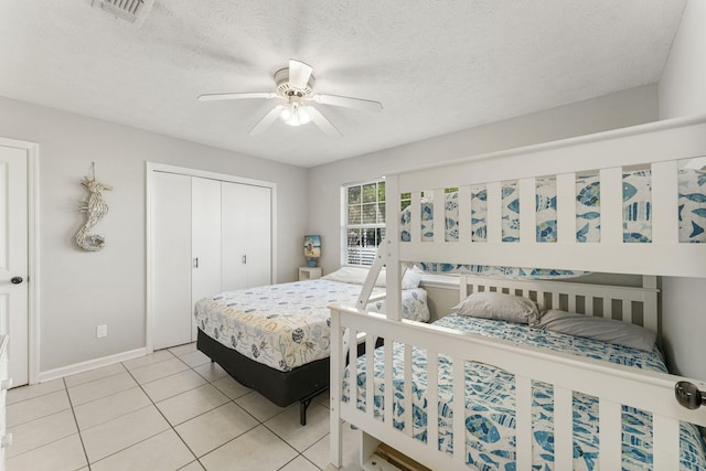 tiled bedroom featuring ceiling fan, a textured ceiling, and a closet