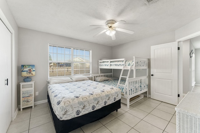 bedroom featuring a closet, ceiling fan, light tile patterned floors, and a textured ceiling