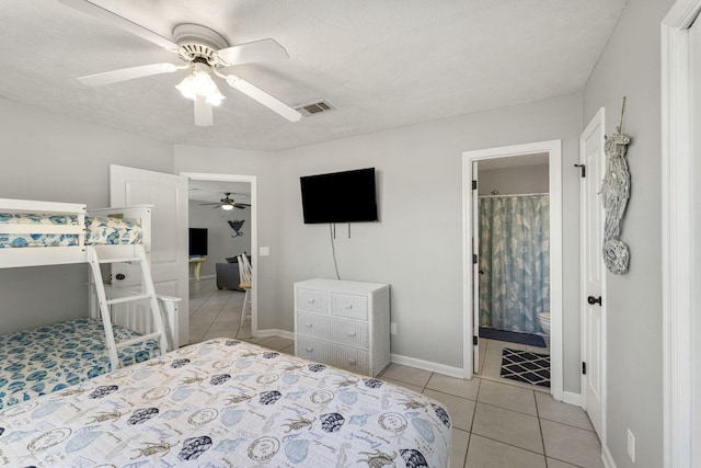 bedroom with a textured ceiling, light tile patterned floors, ceiling fan, and ensuite bathroom