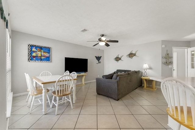 living room featuring ceiling fan, a textured ceiling, and light tile patterned floors