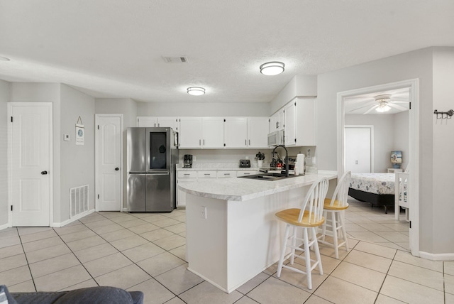 kitchen featuring light tile patterned flooring, white cabinets, a kitchen breakfast bar, appliances with stainless steel finishes, and ceiling fan