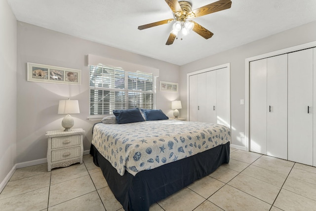 tiled bedroom featuring ceiling fan and multiple closets