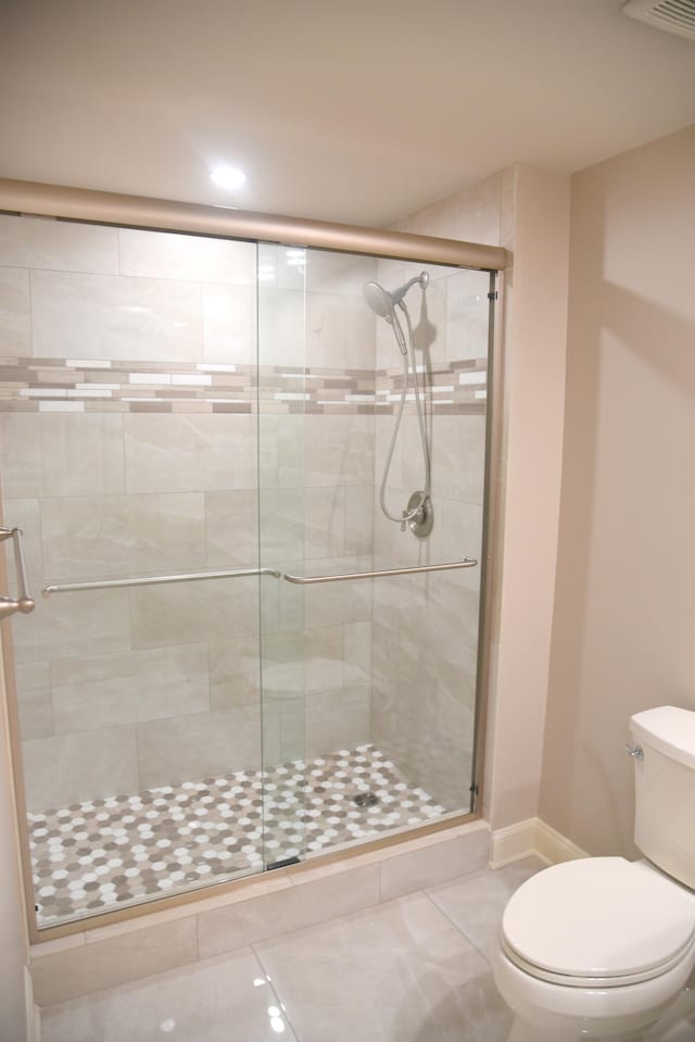 bathroom featuring a shower with shower door, toilet, and tile patterned floors