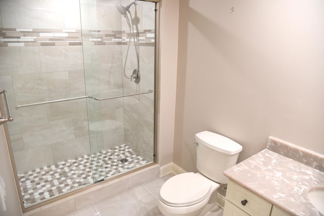 bathroom with tile patterned flooring, walk in shower, vanity, and toilet