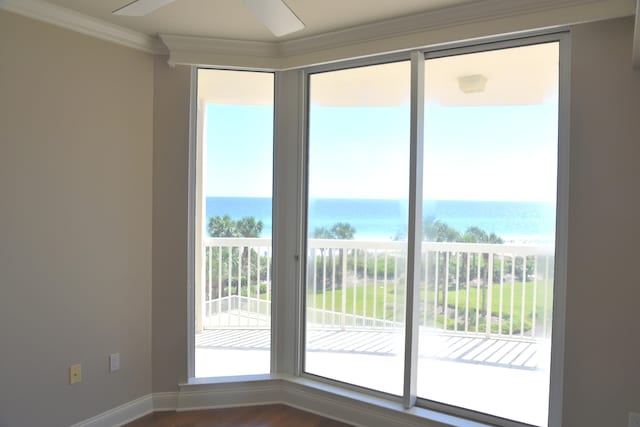 interior space with ceiling fan, ornamental molding, a view of the beach, wood-type flooring, and a water view