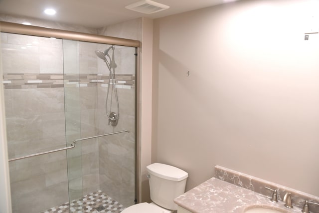 bathroom with a shower with shower door, vanity, and toilet