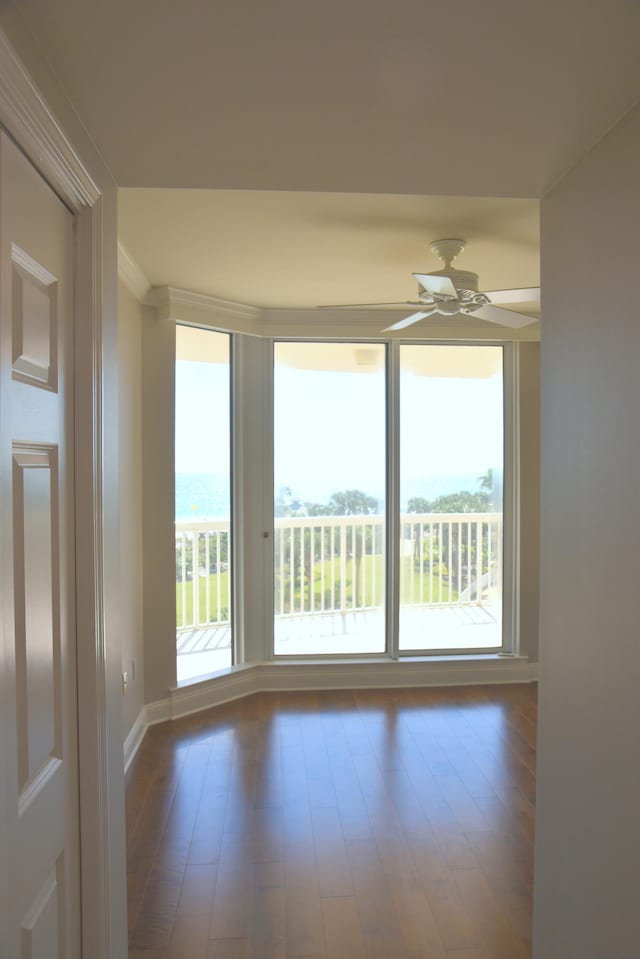 unfurnished room featuring ceiling fan, hardwood / wood-style flooring, and a water view