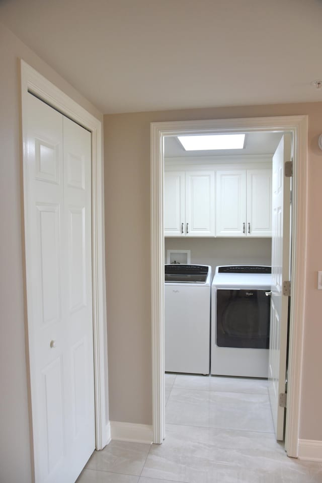 laundry room featuring separate washer and dryer, cabinets, and light tile patterned flooring