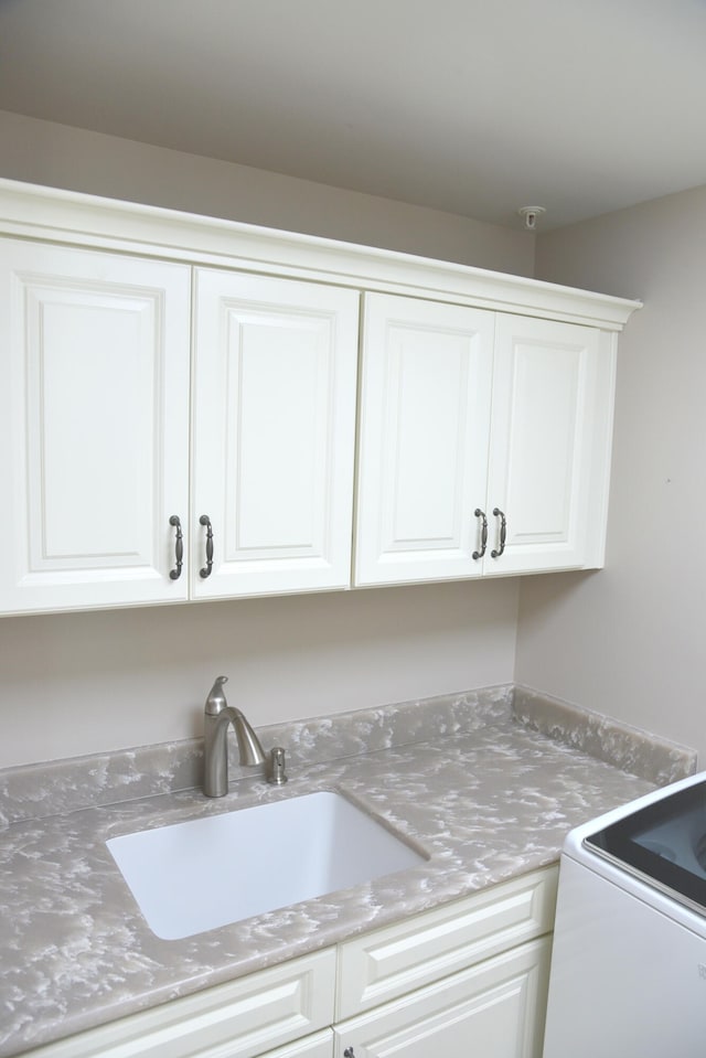 laundry area with cabinets and sink