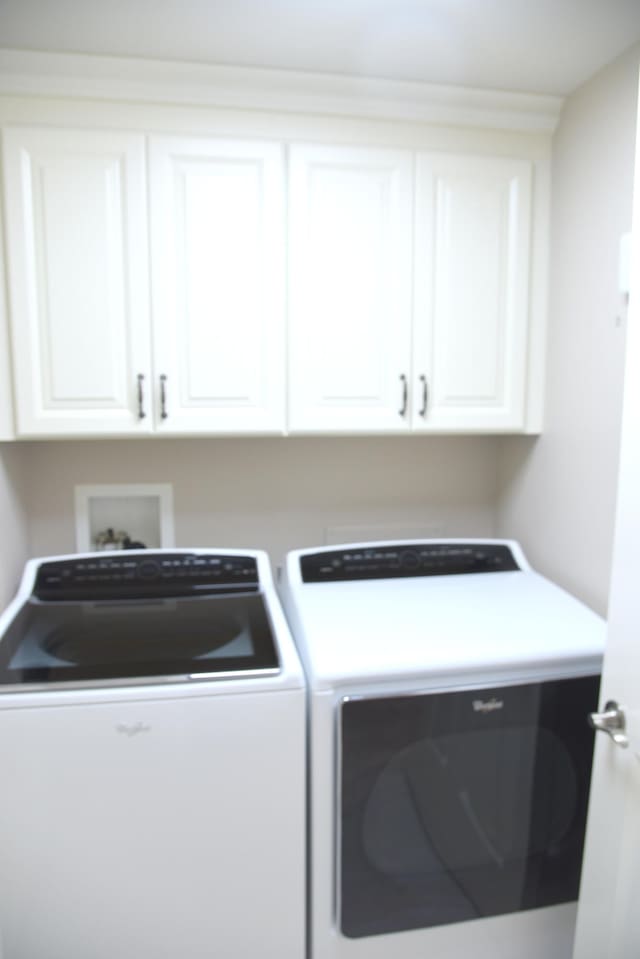 washroom featuring washing machine and clothes dryer and cabinets