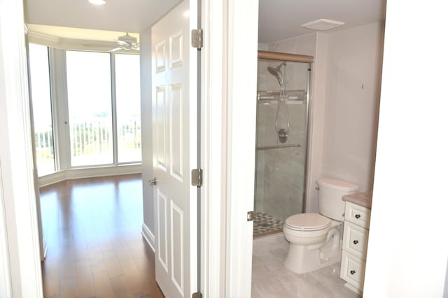 bathroom with ceiling fan, vanity, a shower with shower door, and toilet