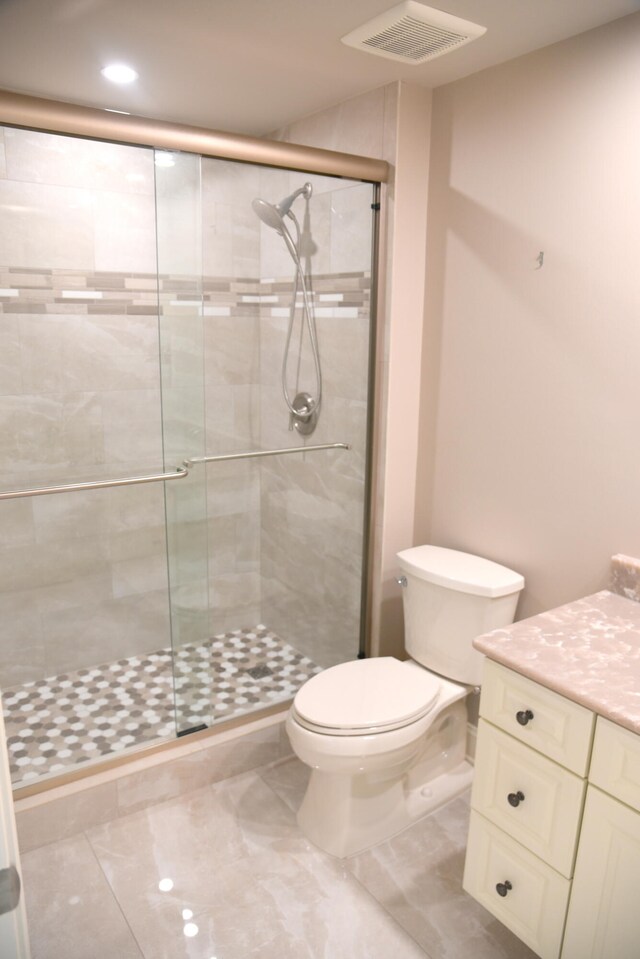 bathroom featuring vanity, a shower with shower door, toilet, and tile patterned flooring