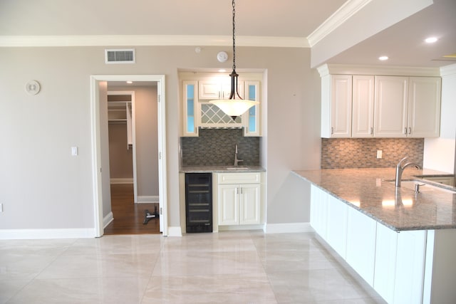 kitchen with pendant lighting, wine cooler, sink, kitchen peninsula, and white cabinetry