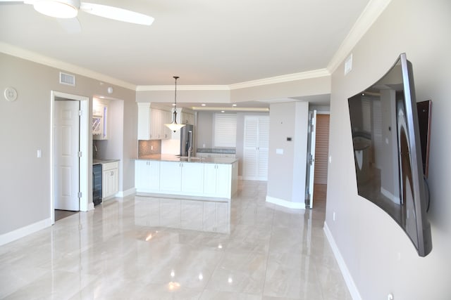 kitchen with pendant lighting, crown molding, white cabinets, and ceiling fan