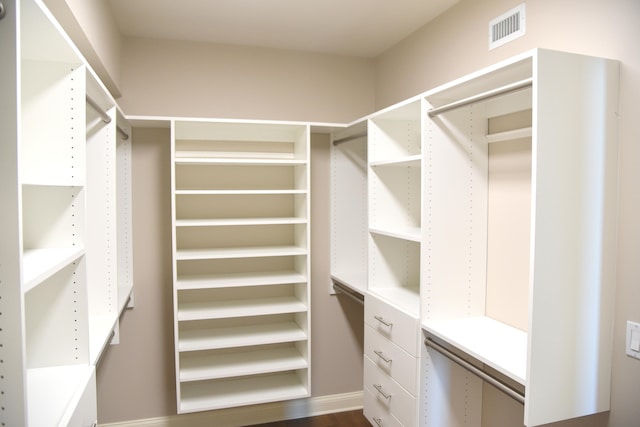 walk in closet with dark wood-type flooring