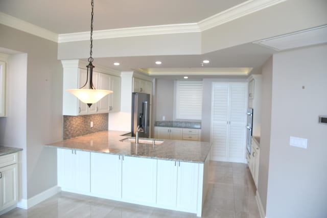 kitchen with stainless steel fridge, kitchen peninsula, pendant lighting, and sink