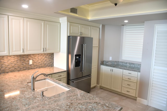 kitchen featuring stainless steel fridge, light stone counters, sink, and tasteful backsplash