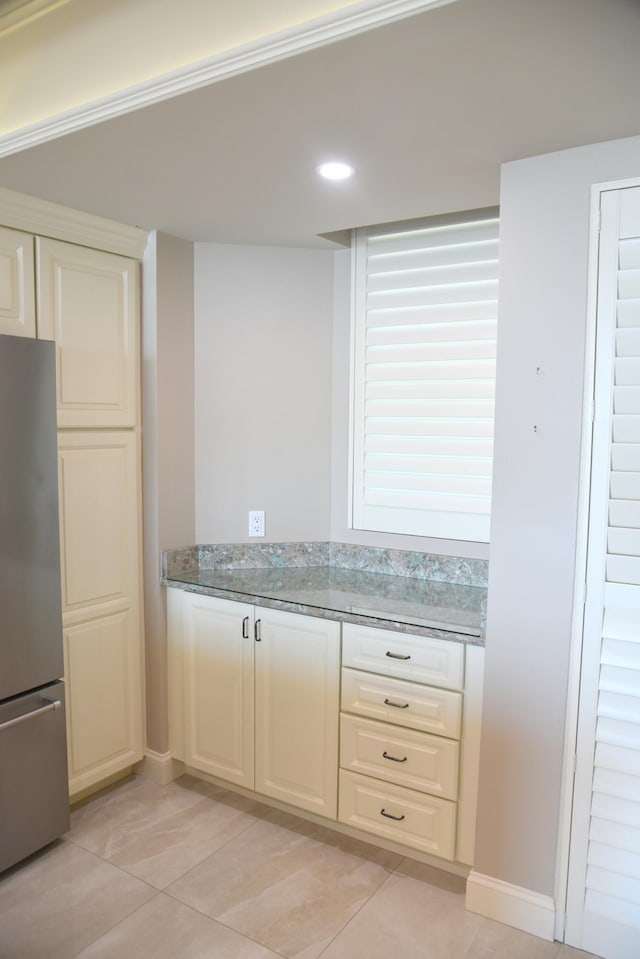 kitchen featuring light stone counters, stainless steel refrigerator, and light tile patterned flooring