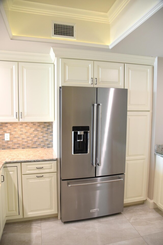 kitchen featuring crown molding, high end refrigerator, light stone counters, decorative backsplash, and light tile patterned floors