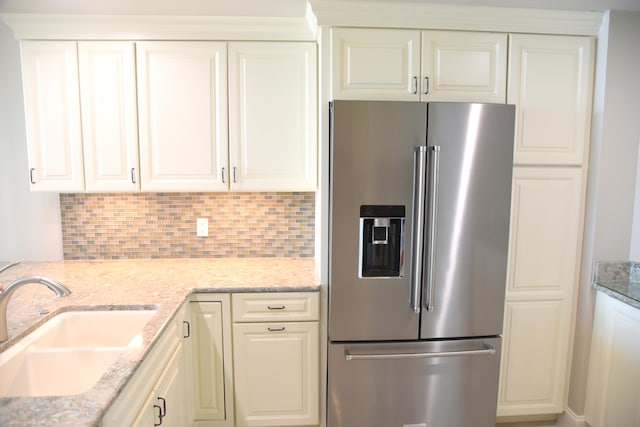 kitchen with light stone countertops, stainless steel fridge, and sink