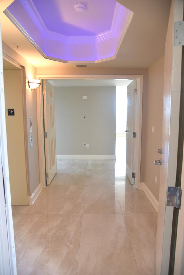 hallway with a raised ceiling and crown molding