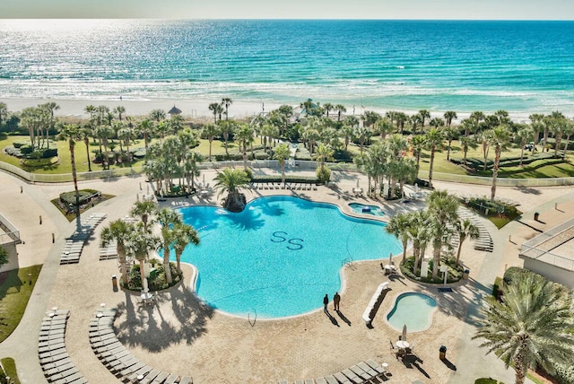 view of pool with a view of the beach, a water view, and a patio