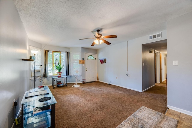 interior space with ceiling fan, a textured ceiling, and carpet flooring