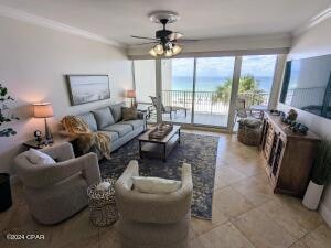 tiled living room with ornamental molding and ceiling fan