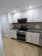 6415 Thomas Dr Unit 205, Panama City Beach, FL 32408 - kitchen featuring appliances with stainless steel finishes, white cabinets, light tile patterned floors, recessed lighting, and decorative backsplash
