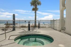 view of swimming pool featuring a community hot tub, a water view, and a patio area