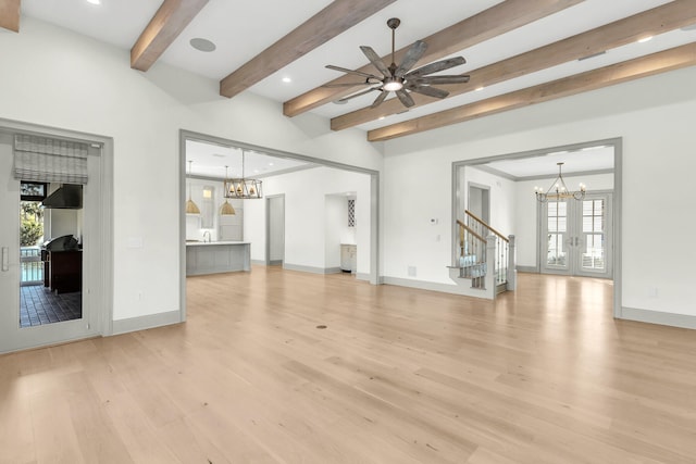 unfurnished living room with beamed ceiling, ceiling fan with notable chandelier, light hardwood / wood-style floors, and a healthy amount of sunlight