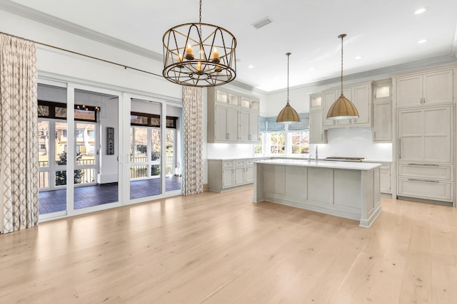 kitchen featuring an island with sink, light hardwood / wood-style floors, pendant lighting, and a notable chandelier