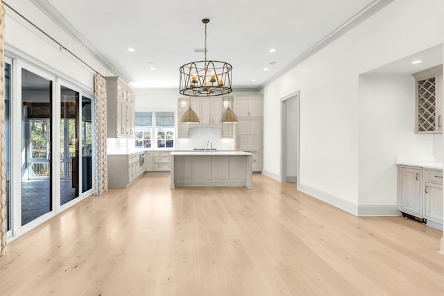 kitchen featuring light hardwood / wood-style flooring, a center island with sink, hanging light fixtures, and crown molding