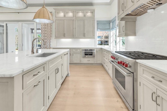 kitchen featuring hanging light fixtures, sink, light hardwood / wood-style flooring, stainless steel appliances, and decorative backsplash