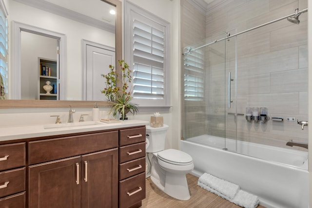 full bathroom featuring vanity, crown molding, toilet, bath / shower combo with glass door, and hardwood / wood-style floors