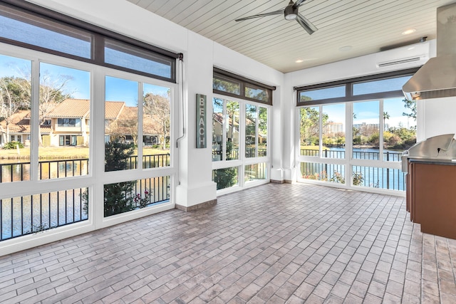 unfurnished sunroom with an AC wall unit, a water view, and ceiling fan