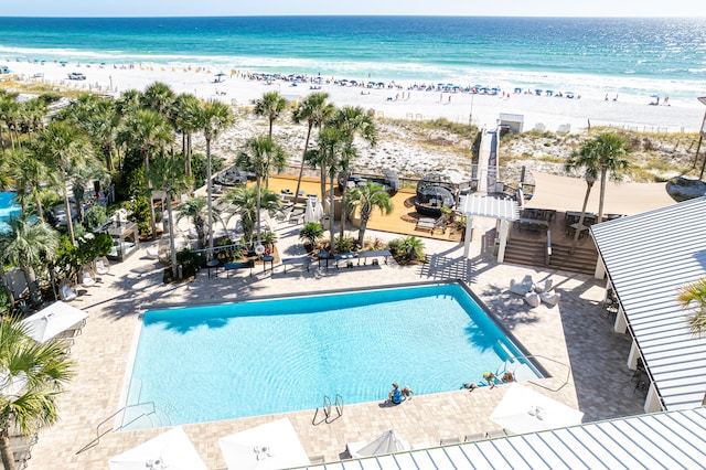 view of pool with a beach view, a water view, and a patio area