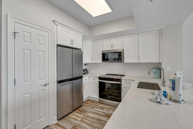 kitchen featuring white cabinets, appliances with stainless steel finishes, light wood-type flooring, and sink