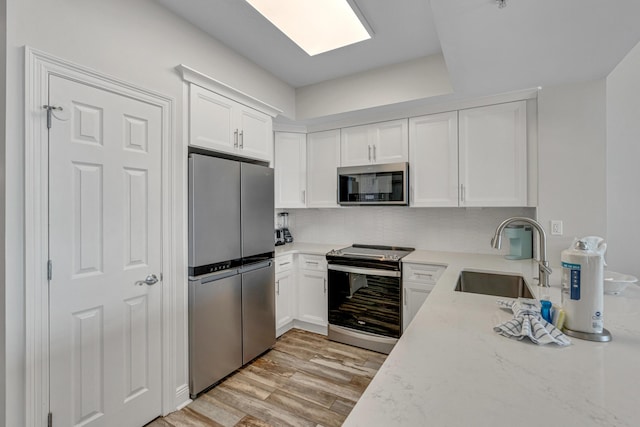 1111 Santa Rosa Blvd Unit 604, Fort Walton Beach, FL 32548 - kitchen with white cabinets, a sink, appliances with stainless steel finishes, and light wood-style flooring