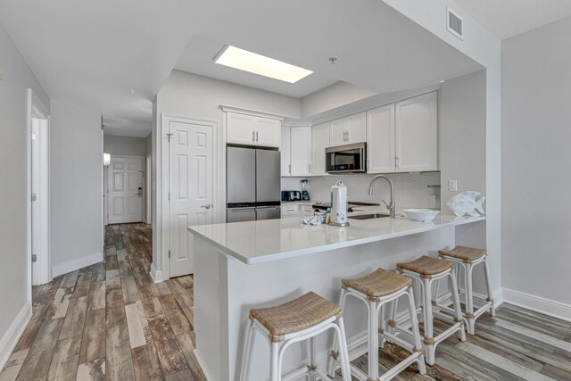 kitchen with appliances with stainless steel finishes, a kitchen bar, and white cabinetry