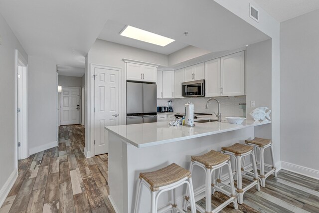 1111 Santa Rosa Blvd Unit 604, Fort Walton Beach, FL 32548 - kitchen featuring white cabinets, visible vents, wood finished floors, appliances with stainless steel finishes, and a sink