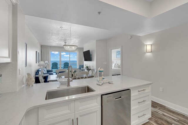 kitchen featuring white cabinets, sink, wood-type flooring, dishwasher, and an inviting chandelier