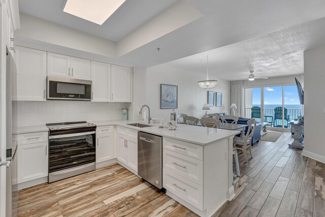 kitchen with appliances with stainless steel finishes, white cabinetry, sink, and ceiling fan