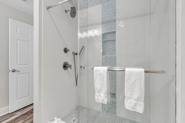 bathroom with wood-type flooring and a shower with shower door