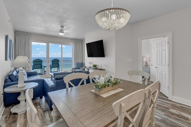 dining space with a textured ceiling, ceiling fan with notable chandelier, and hardwood / wood-style floors