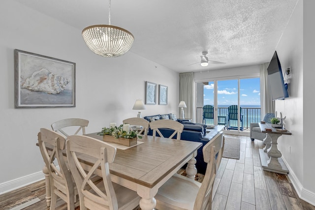 1111 Santa Rosa Blvd Unit 604, Fort Walton Beach, FL 32548 - dining space featuring ceiling fan with notable chandelier, light wood-style flooring, baseboards, and a textured ceiling