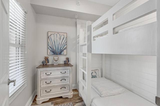 bedroom featuring wood walls, multiple windows, and dark wood-type flooring