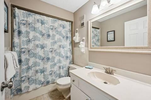 full bathroom featuring tile patterned floors, shower / bath combo, vanity, and toilet